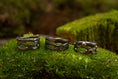 Bild in Galerie-Betrachter laden, Udstillet på en seng af frodig grøn mos er tre indviklet designede mørke metalringe med naturinspirerede mønstre, hver prydet med små ædelsten. Disse ringe, kaldet Fingerring - Eryn Design - Moria (Simpel), fremviser en organisk, sammenflettet struktur, der ligner kviste eller grene. De er perfekte eksempler på håndlavede smykker.