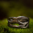 Bild in Galerie-Betrachter laden, Et nærbillede af en rustik, sølvfarvet ring på en bund af grønt mos. Denne fingerring - Eryn Design - Moria (Simpel) har et organisk, sammenflettet design med uregelmæssige åbninger, hvilket giver den et naturligt og robust udseende. Baggrunden er sløret, hvilket understreger teksturen og detaljerne i dette stykke dansk design håndlavede smykker.