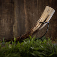 Bild in Galerie-Betrachter laden, En poleret Drikkehorn Basic uden holder hviler vandret på et metalstativ. Hornet har nuancer af creme, brun og sort, sat mod en rustik træbaggrund. Grønt er synligt i forgrunden og tilføjer et strejf af natur, der minder om gammel vikingemarkeder.