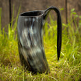 Bild in Galerie-Betrachter laden, Et Vikingekrus Nature Horn (600-800ml) med et håndtag, prydet i et marmoreret sort og gråt mønster, står oprejst på græsklædt terræn med en træbaggrund. Dette stykke legemliggør essensen af vikingekrus, der forener tradition og håndværk.