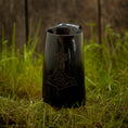 Bild in Galerie-Betrachter laden, Et Vikingekrus Thors Hammer Horn (600-800 ml) med et indgraveret design, der ligner Thors Hammer, hviler på en plet græs, med en forvitret trævæg i baggrunden.