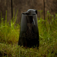 Bild in Galerie-Betrachter laden, Et sort keramik Vikingekrus Thors Hammer Horn (600-800ml) med et håndtag og en tud, med et stiliseret Thors hammerdesign ætset på forsiden, er placeret på en plet af grønt græs mod en træbaggrund. Denne vikingekrus udstråler robust charme.