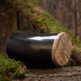 Bild in Galerie-Betrachter laden, Ein poliertes schwarzes Trinkglas Horn Plain (500ml) mit glattem Holzboden steht auf einer rustikalen Oberfläche, umgeben von Grün und Baumrinde. Der Hintergrund aus Holzplanken betont die natürliche, erdige Atmosphäre.