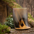 Bild in Galerie-Betrachter laden, Ein poliertes Trinkglas Horn Plain (500 ml) mit geschwungenem Design und Holzboden ruht auf einem moosbedeckten Baumstamm. Im Hintergrund ist eine rustikale Holzfläche zu sehen, teilweise mit grünem Moos und Laub geschmückt.