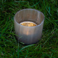 Bild in Galerie-Betrachter laden, Lysestage til fyrfadslys, en sofistikeret sølv lysestage med guld interiør, sidder på frodigt grønt græs. Holderen er skinnende og reflekterende, mens græsset omkring den er levende og nyklippet.