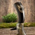 Bild in Galerie-Betrachter laden, Drikkehorn Yggdrasil U. Mønster er udstillet opretstående på en træstub, omgivet af grønt mos og planter. Dette elegante drikkehorn har indviklede udskæringer med bladmotiver ætset ind i overfladen, der minder om gamle vikingermærkede skatte og påkalder Yggdrasils ånd.