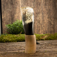 Bild in Galerie-Betrachter laden, En dekorativ Drikkehorn Templar med et udskåret pentagram-symbol vises opretstående på en rustik træoverflade. Grønt løv og en trækulisse danner en naturlig ramme om det polerede bøffelhorn, der minder om vikingemarkeder.