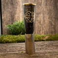 Bild in Galerie-Betrachter laden, En poleret, mørkfarvet Drikkehorn Templar med guldkant og dekorativt knudedesign sidder på en træoverflade. Scenen har grønt mos og planter i baggrunden, der fremkalder vikingemarkedernes rustikke, naturlige stemning.