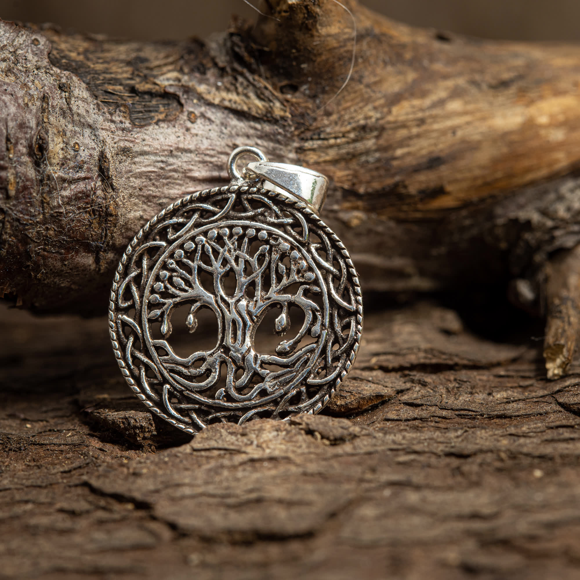 Yggdrasil Livets Træ Vedhæng Celtic 925s Sølv vedhæng, med et indviklet livstræ-design, hviler på en tekstureret træbaggrund. 925s Sterling Sølv-stykket viser detaljerede grene og rødder inden for en cirkulær ramme, der fanger essensen af det keltiske mønster.