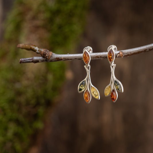 Ein Paar elegante Hängeohrringe Boroi 925s Silber, aus 925s Silber gefertigt und mit mehrfarbigen Edelsteinen besetzt, hängt an einem kurzen Ast. Jede Ohrstecker hat ein geschwungenes Silberdesign mit vier kleinen, marquiseförmigen Steinen in Grün, Bernstein und Gelb auf verschwommenem, erdigem Hintergrund.